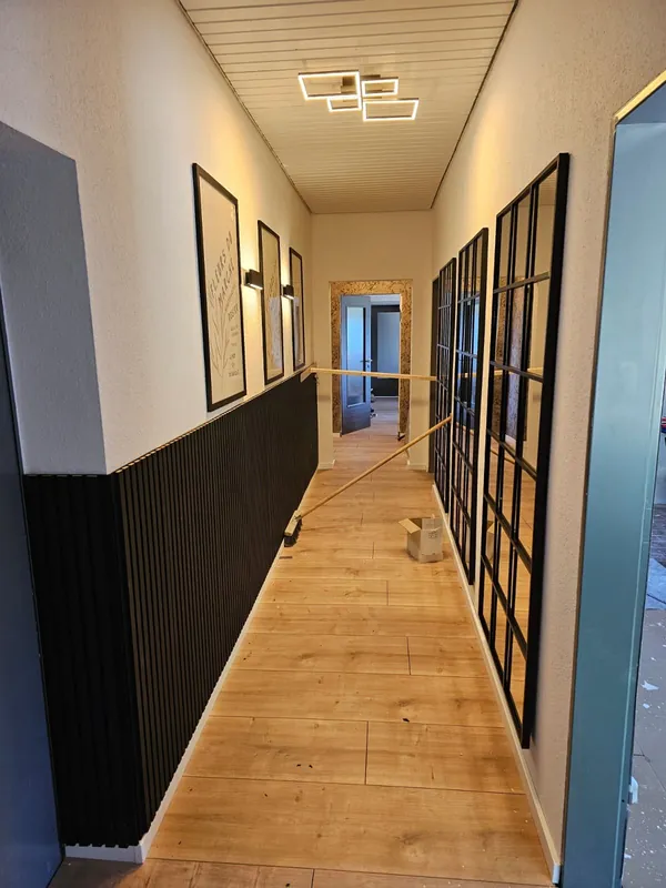 Renovierter Flur mit dunklem Wandsockel und hellen Bodenplatten